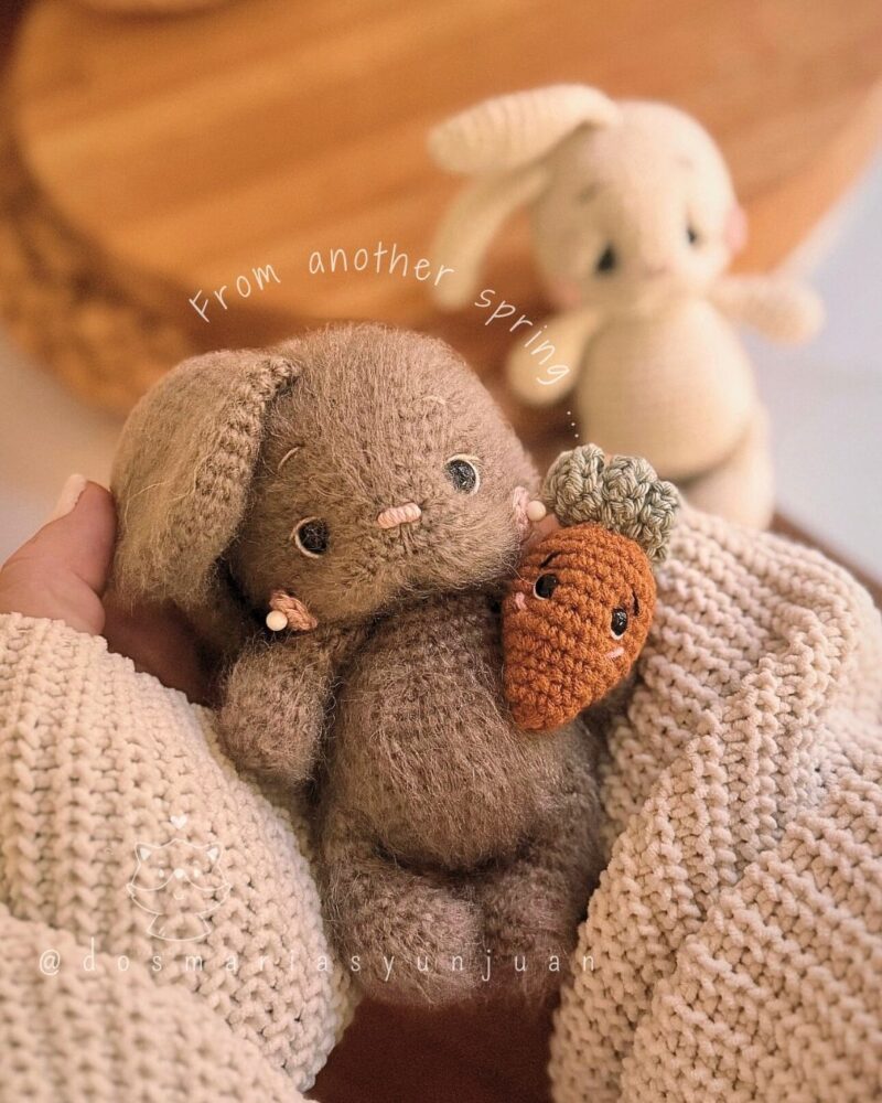 Vintage furry brown crochet bunny holding a carrot, close-up view.