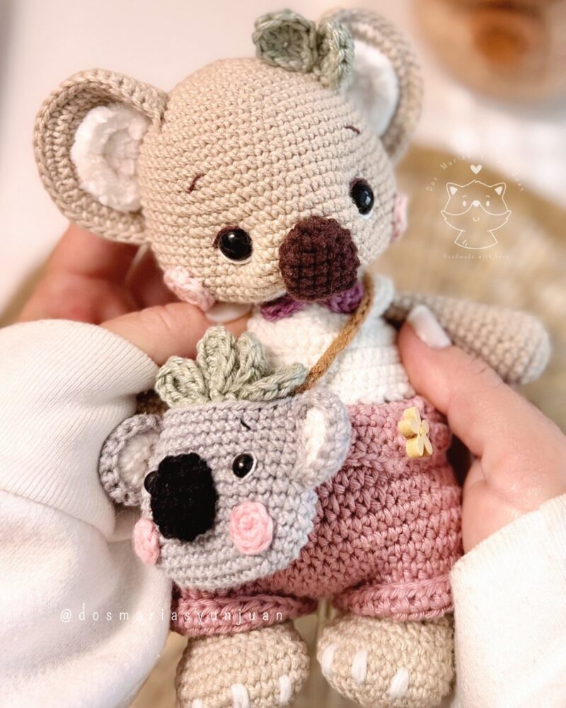 Close-up of Benna the crochet koala showing detailed features of her face and mini backpack. Soft handmade details and pastel colors by Dos Marías y un Juan.