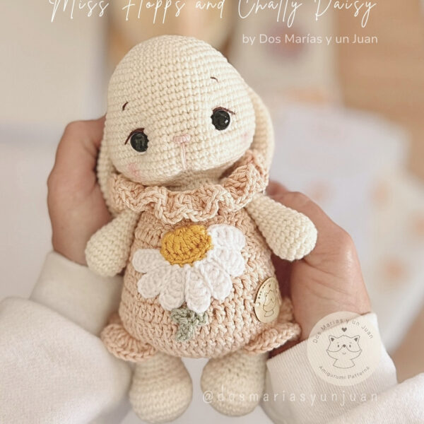 Miss Flopps amigurumi bunny holding a daisy flower, handmade crochet pattern by Dos Marías y un Juan