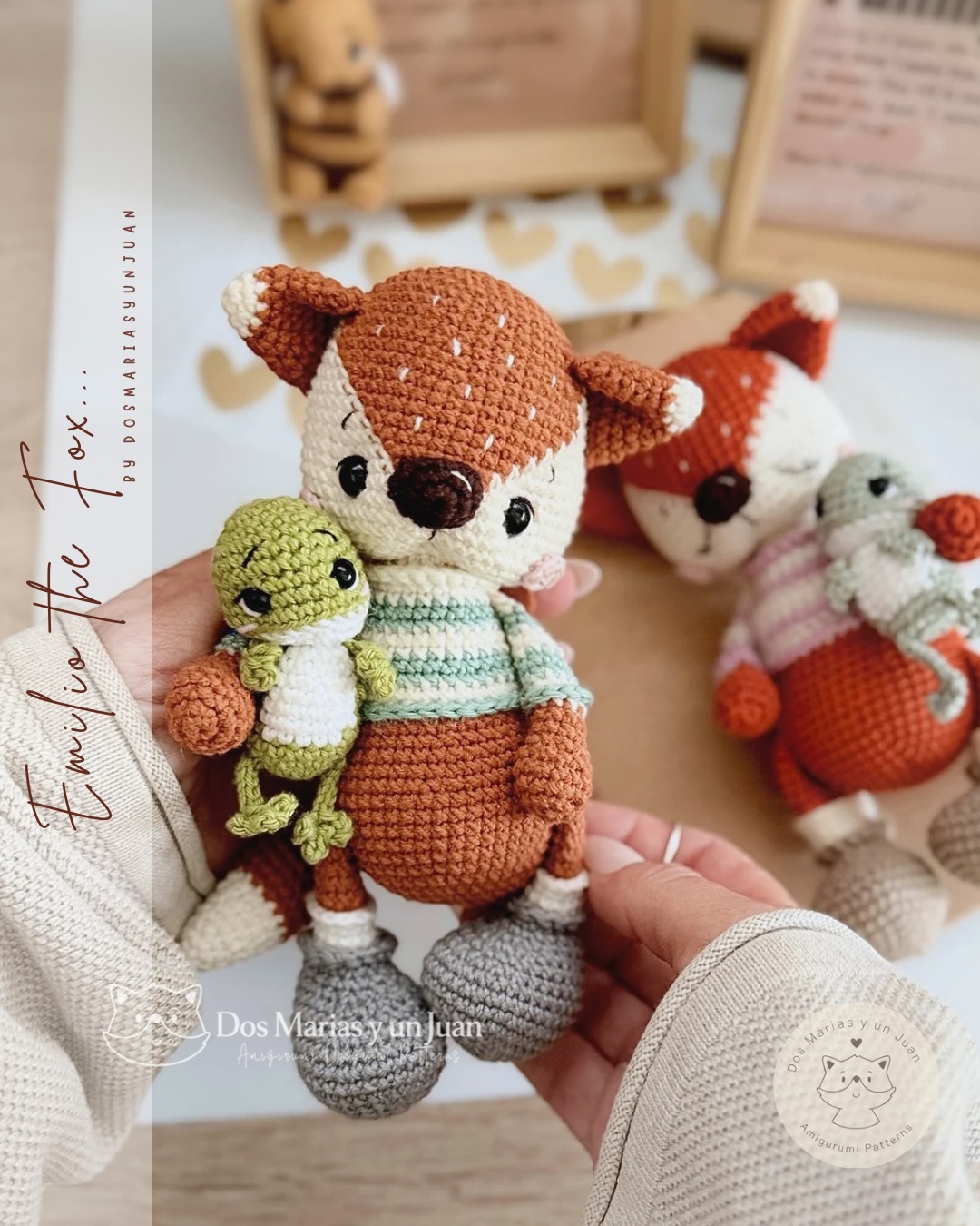 Amigurumi Emilio the Fox holding René the Tree Frog, both handmade in crochet with a striped sweater in cream, sage and mint; sleepy fox variant with pink-striped sweater and mouse companion blurred in the background.